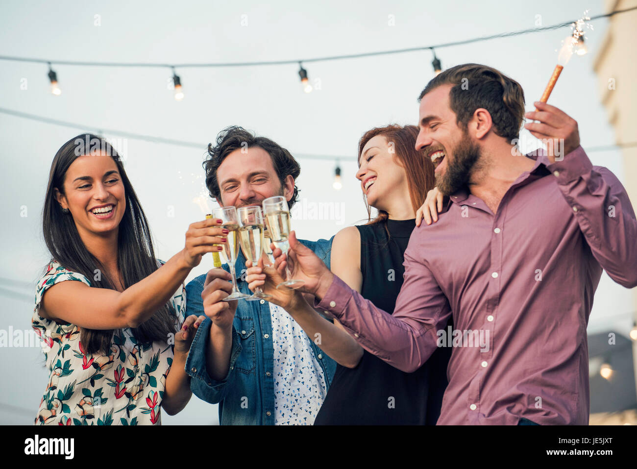 Amici tintinnanti bicchieri da champagne all'aperto Foto Stock