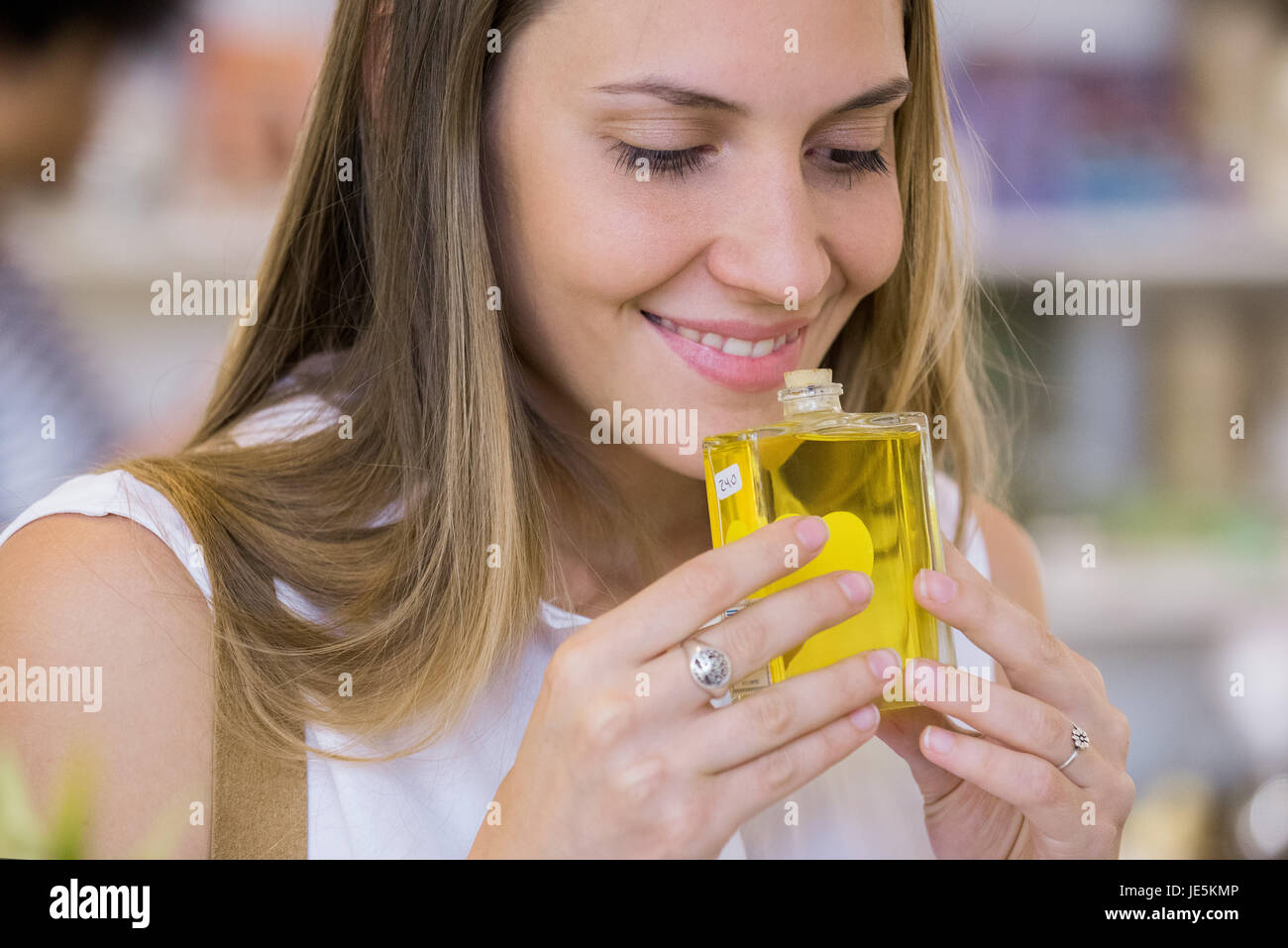 Giovane donna odore di profumo in negozio Foto Stock