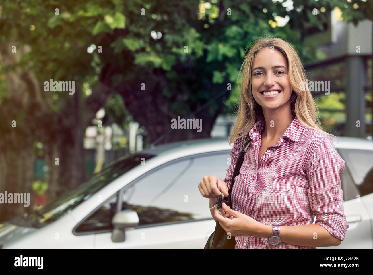 Giovane donna tenendo premuto i tasti AUTO, sorridente allegramente Foto Stock