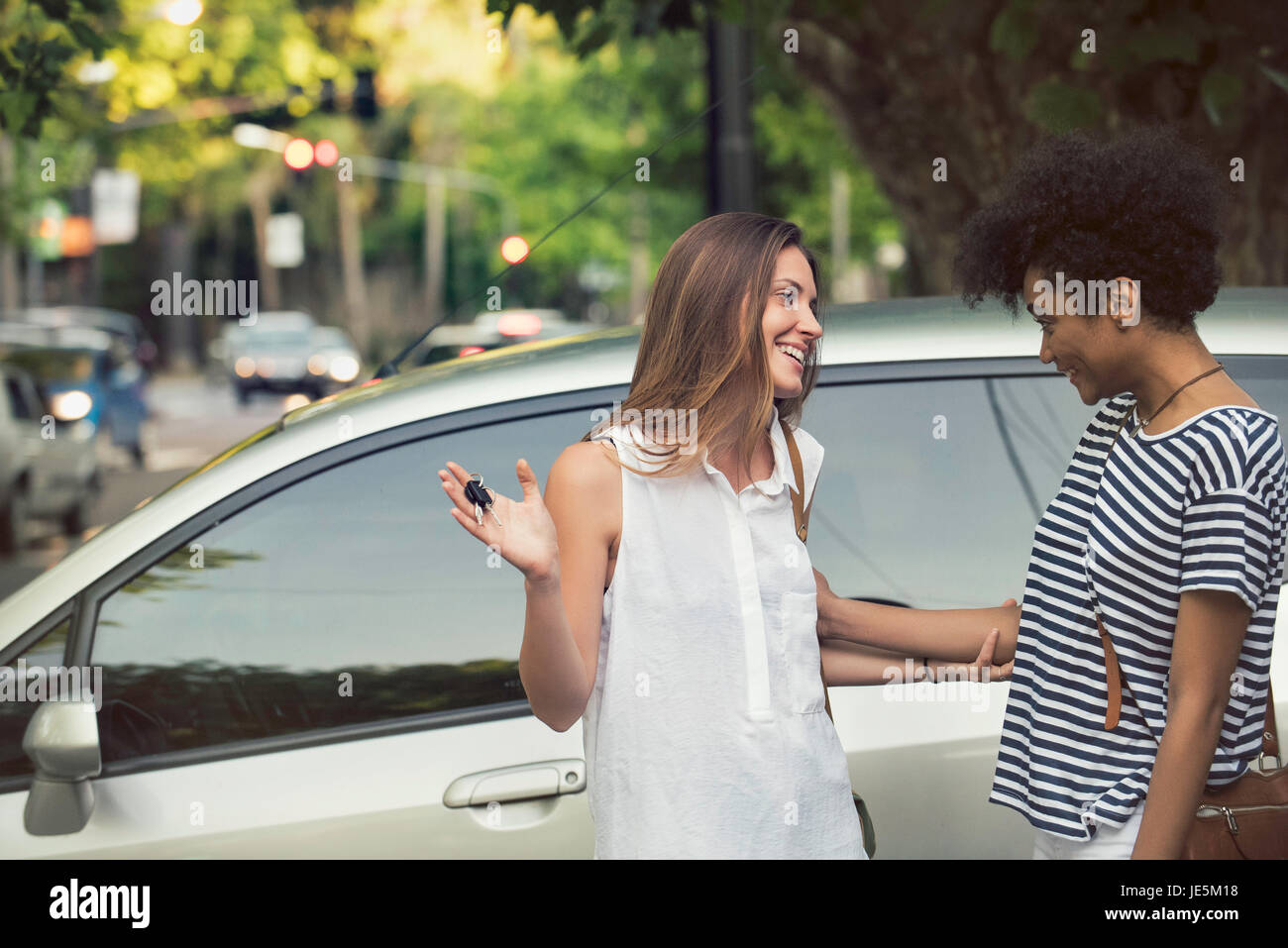 Giovane donna orgogliosamente mostra amico chiavi per auto nuova Foto Stock