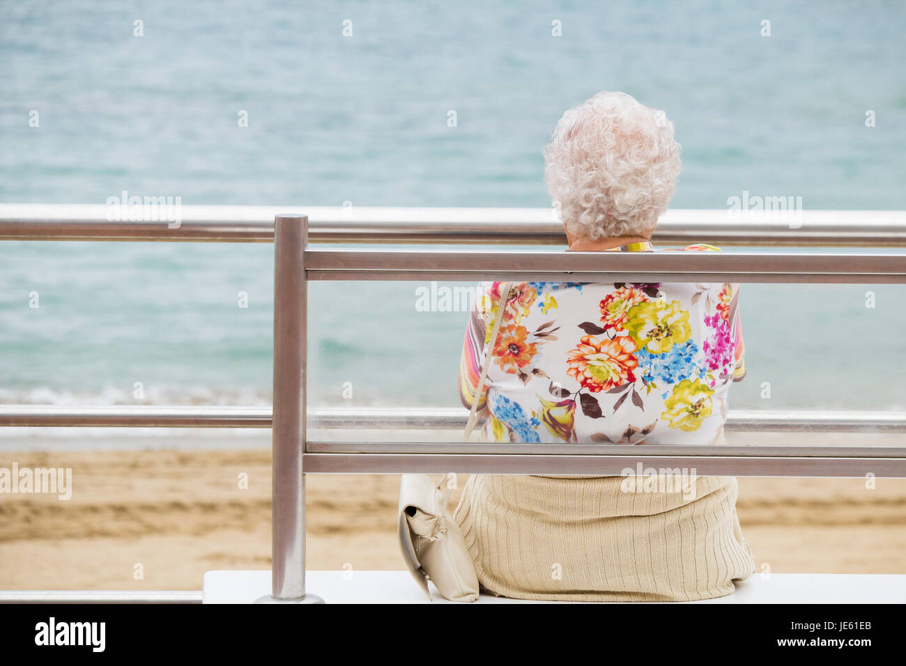 Donna anziana con i capelli bianchi e colorati top seduta sul banco di  prova che si affaccia sul mare Foto stock - Alamy