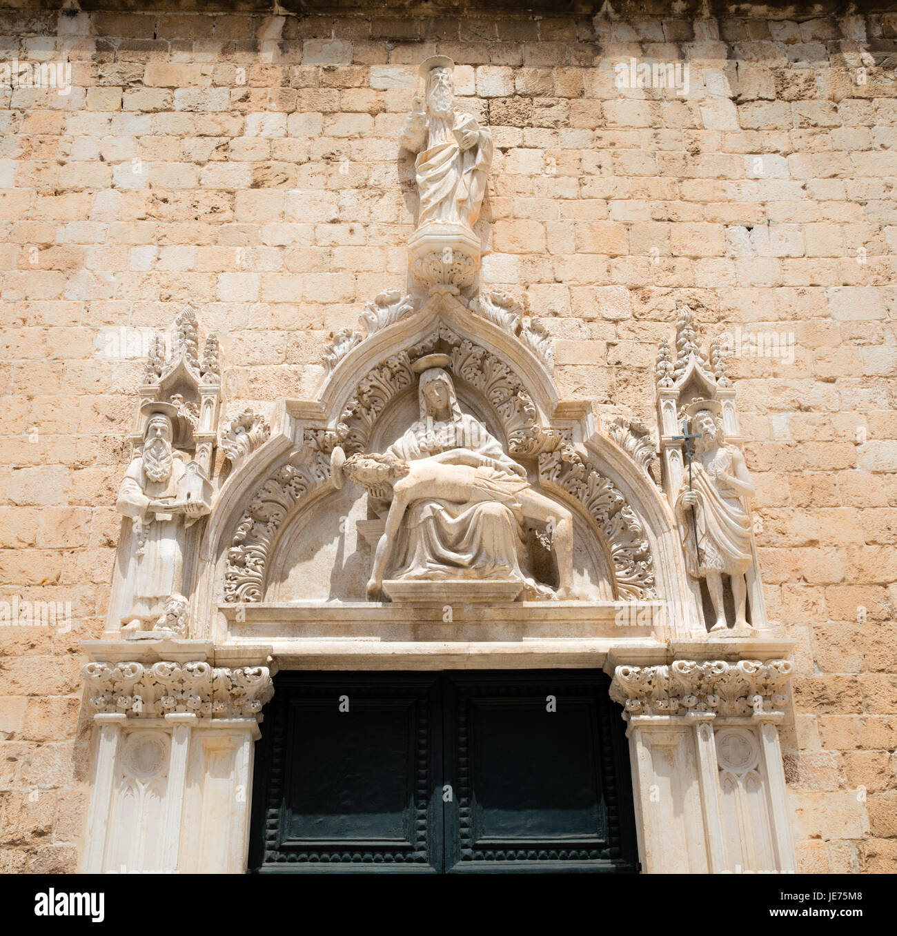 Intagliato frontone in pietra raffigurante il Cristo morto e Maria Maddalena su una porta del monastero francescano sullo Stradun di Dubrovnik in Croazia Foto Stock