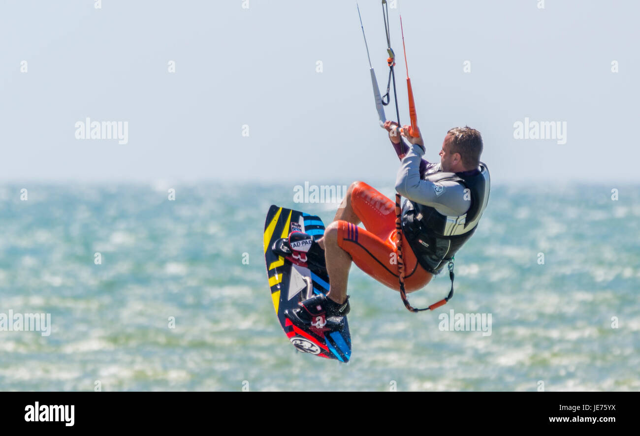 Il kitesurfing. Kitesurfer volare in aria come egli fa uno stunt mentre in mare in una giornata di vento. Foto Stock