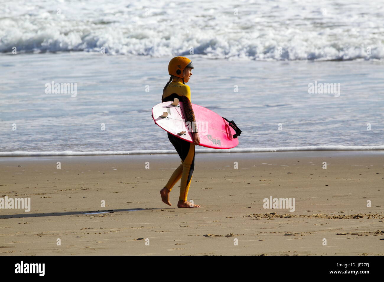 Un giovane preteen surfer girl andando a navigare. Foto Stock