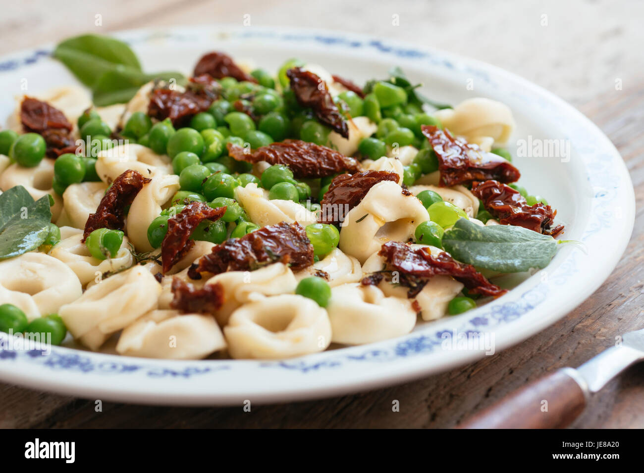 Tortellini con fresco giardino di piselli e pomodori secchi Foto Stock