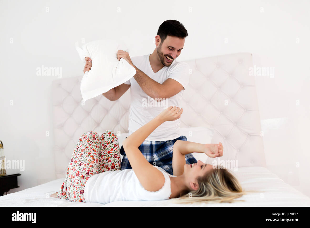 Coppia felice in lotta con i cuscini nel letto Foto stock - Alamy