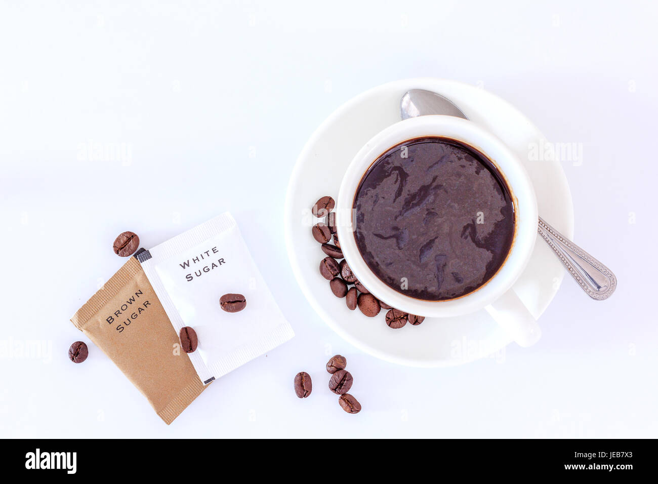 Una tazza di caffè nero e la bustina di zucchero per rinfrescare la mattina, vista dall'alto con spazio copia testo e. Foto Stock