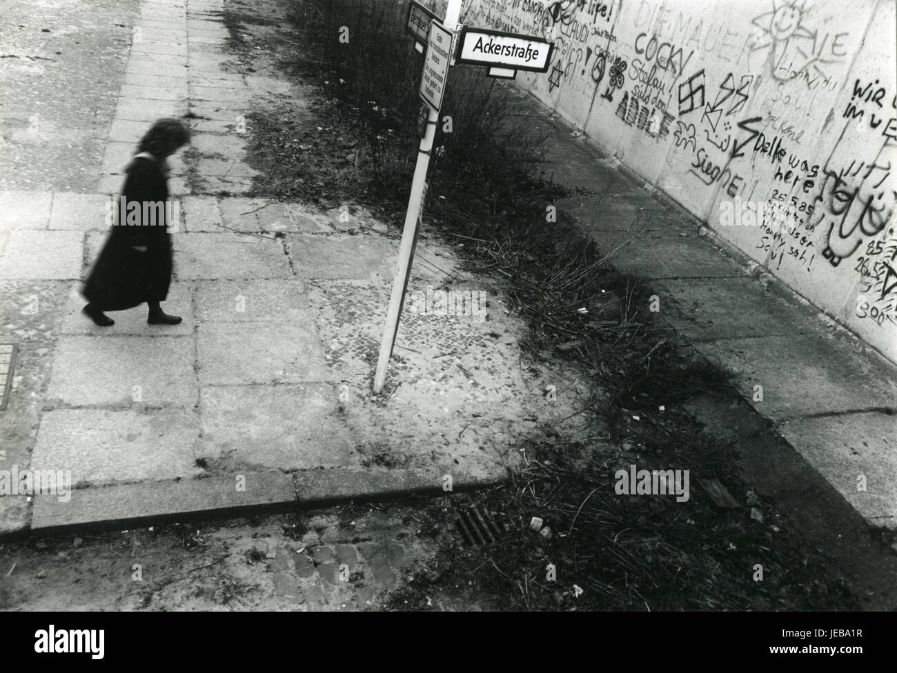 Una signora cammina verso il muro di Berlino in corrispondenza della giunzione di Ackerstraße e Bernauerstraße in Ott 1987 Foto Stock