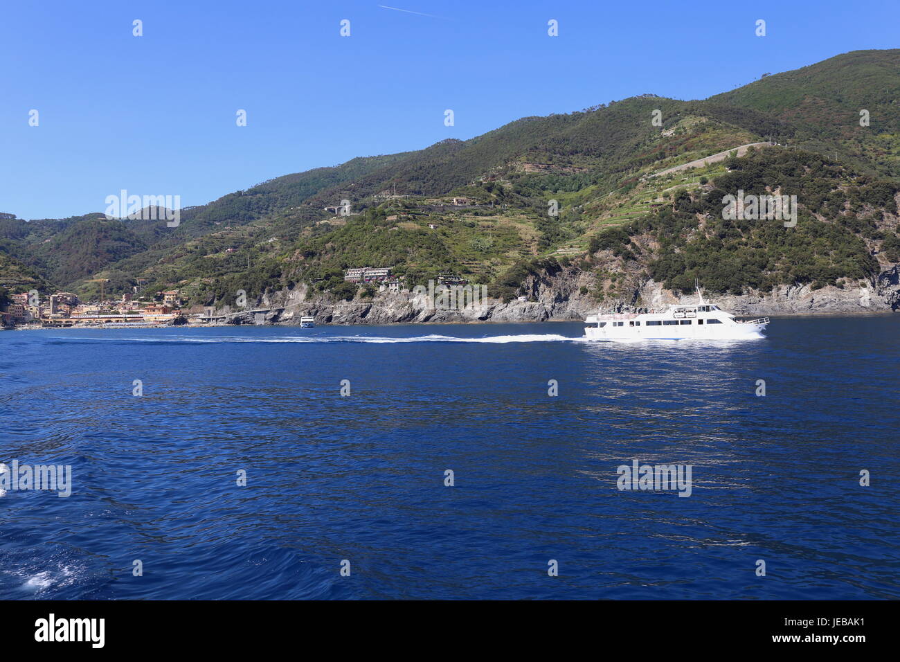 Imbarcazione turistica lasciando Monterosso e che si muove in basso lungo la costa tra i borghi delle Cinque Terre in Italia. Foto Stock