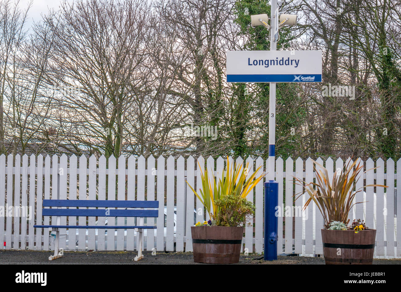 Longniddry stazione ferroviaria segno della piattaforma con panchine, fioriere e white Picket Fence, East Lothian, Scozia, Regno Unito Foto Stock