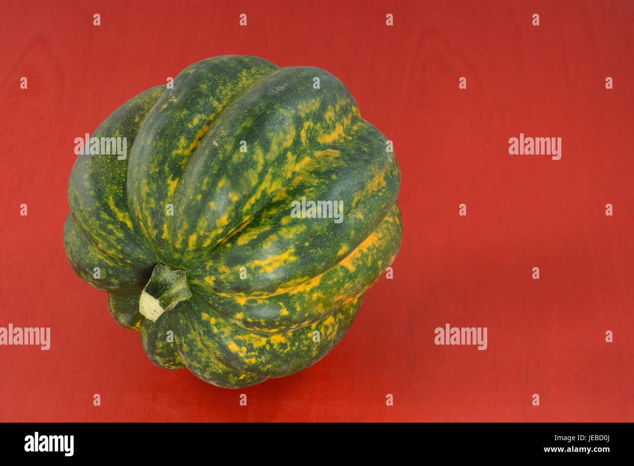 Un crudo intero acorn squash sul legno rosso sfondo tabella Foto Stock