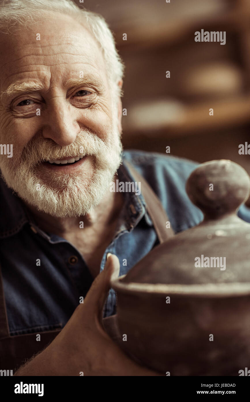 Senior potter nel grembiule esaminando la coppa in ceramica in officina Foto Stock