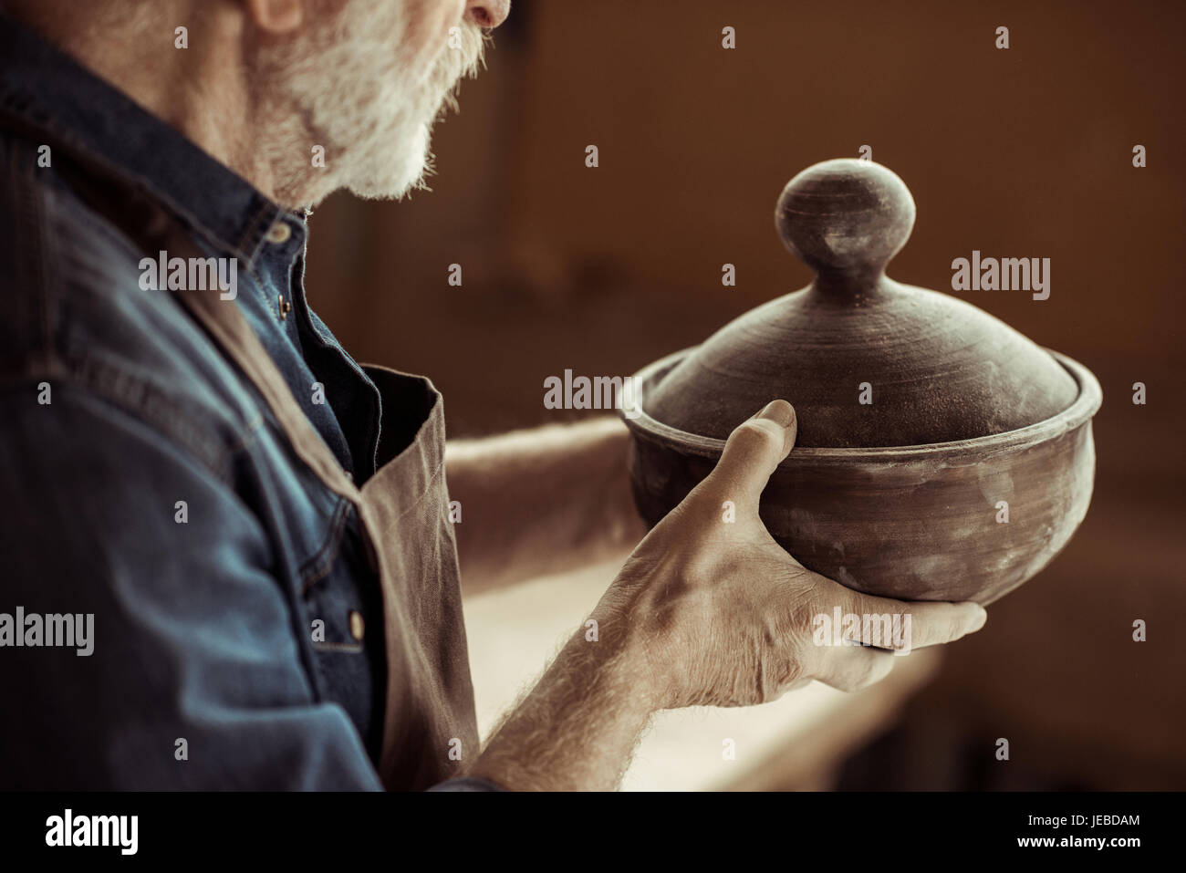Senior potter nel grembiule esaminando la coppa in ceramica in officina Foto Stock