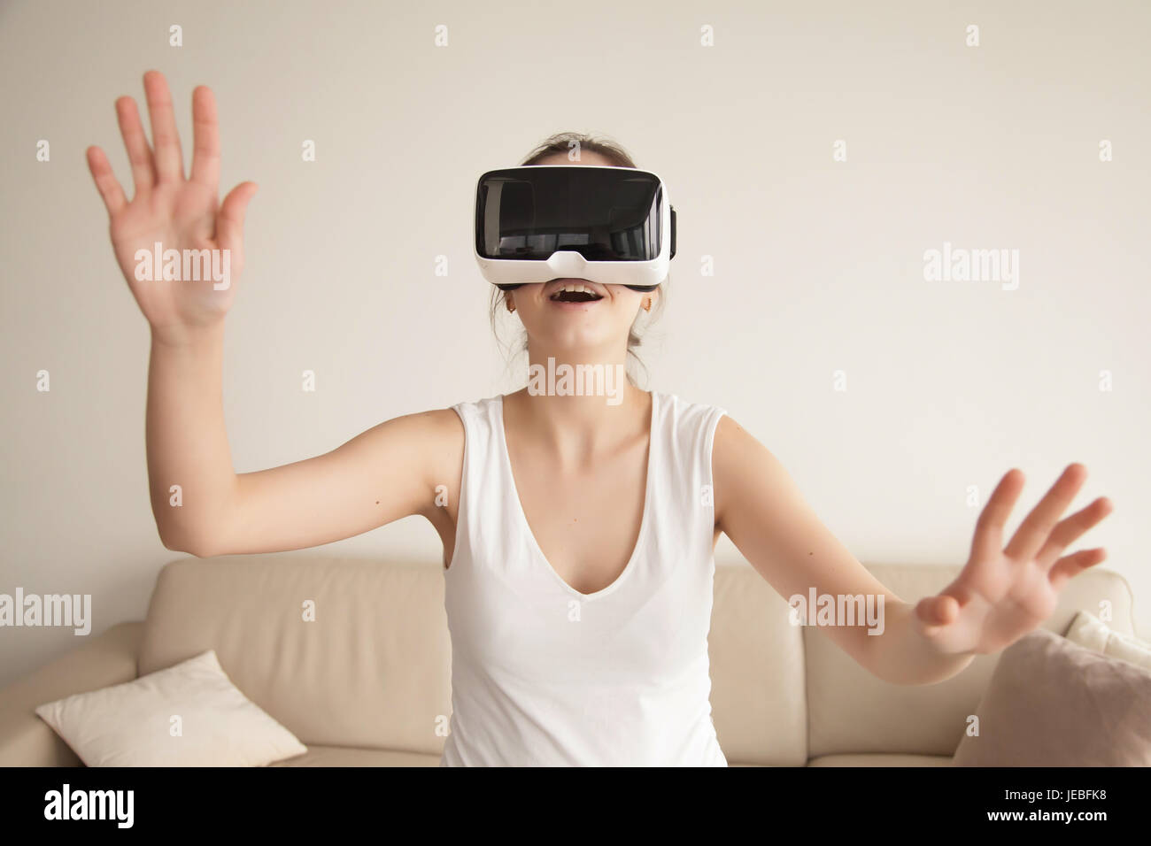 Giovane donna gode di VR videogiochi sul divano di casa Foto Stock