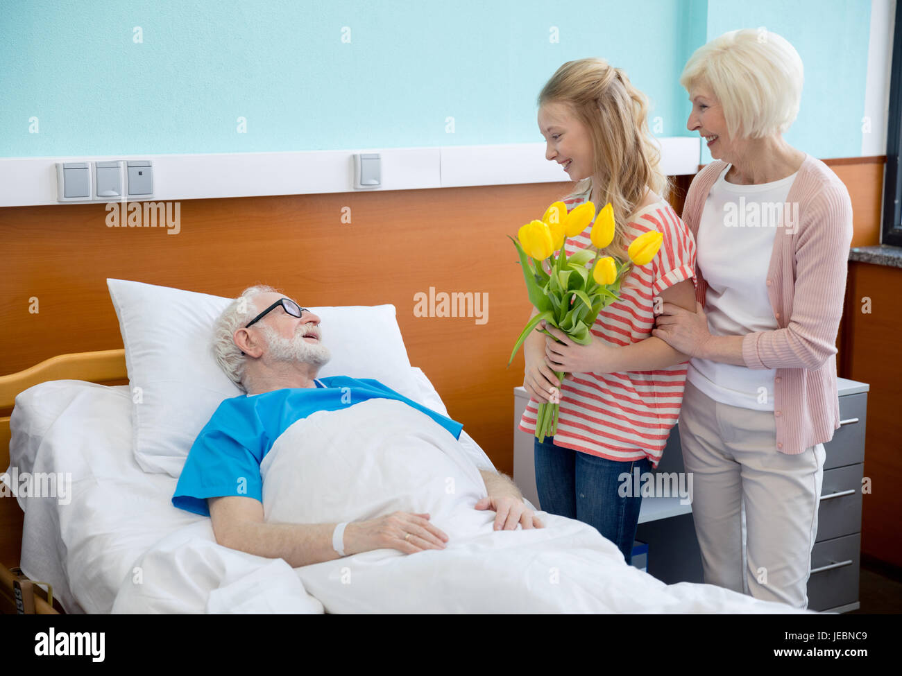 Nonna e nipote con tulip fiori visita il paziente in ospedale. paziente di  sesso maschile nel letto di ospedale concept Foto stock - Alamy