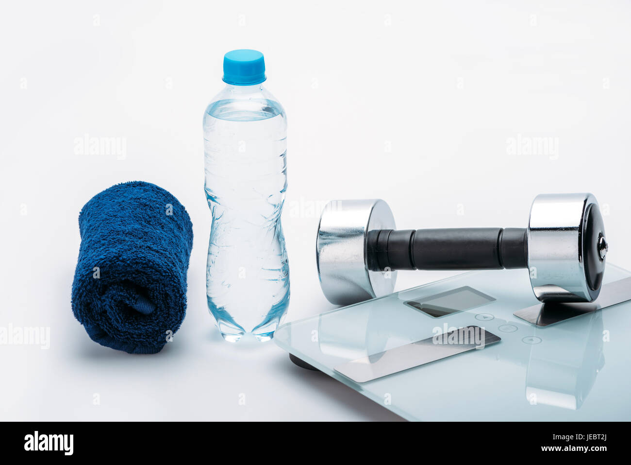 Manubrio metallico, bilance, asciugamano e una bottiglia con acqua isolato su bianco. Bere acqua, attrezzature sportive e uno stile di vita sano concetto Foto Stock