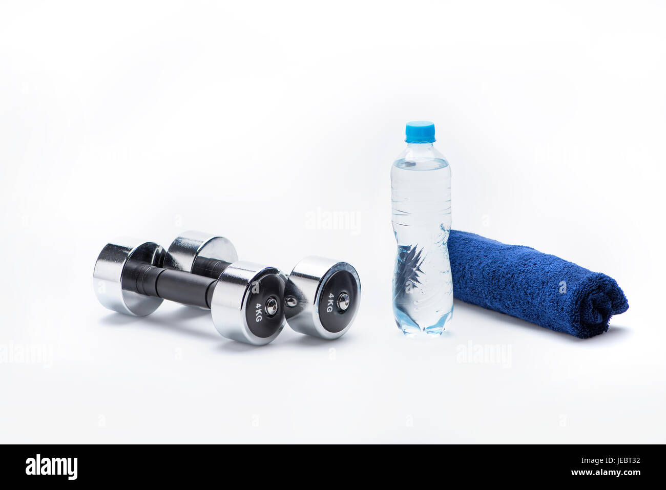 Pesi metallici, asciugamano e una bottiglia con acqua isolato su bianco. Le attrezzature di sport e di uno stile di vita sano concetto Foto Stock