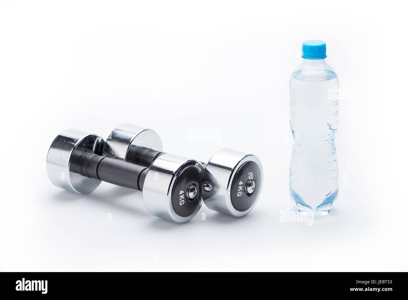 Pesi metallici e una bottiglia con acqua isolato su bianco. Bere acqua, attrezzature sportive e uno stile di vita sano concetto Foto Stock