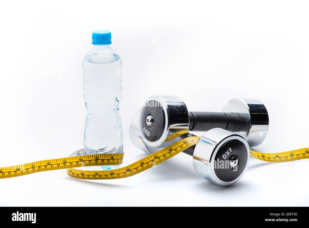 Pesi metallici, bottiglia e nastro di misurazione isolata su bianco. Bere acqua, attrezzature sportive e uno stile di vita sano concetto Foto Stock