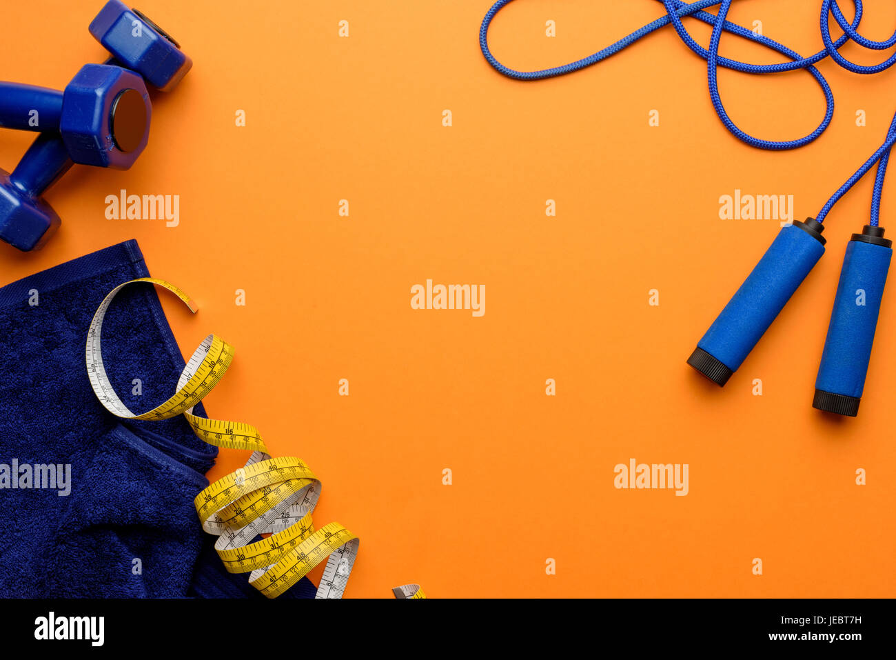 Varie attrezzature sportive, nastro di misurazione e l'asciugamano isolati su Orange Foto Stock