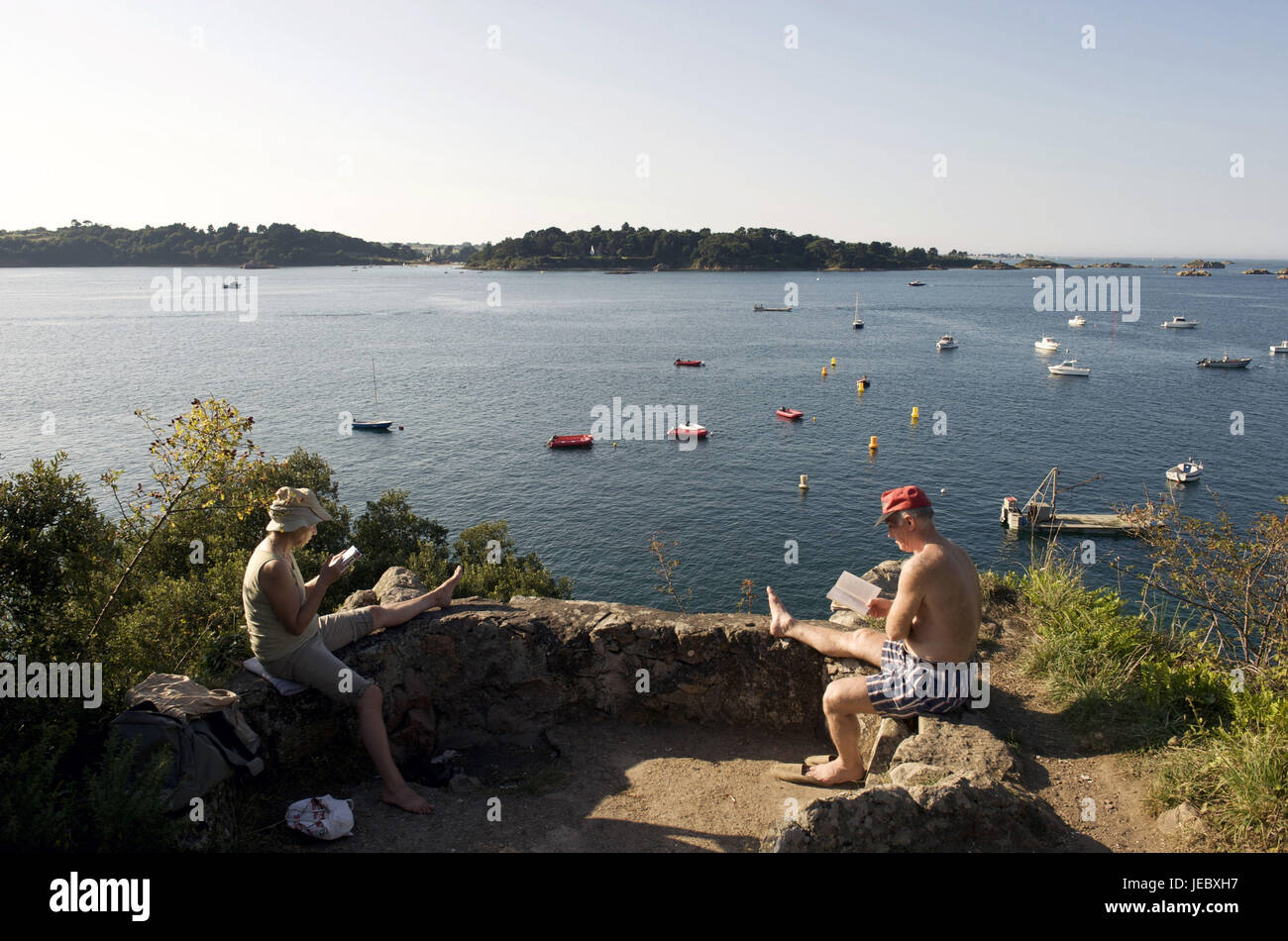 Europa, Francia, Bretagna Loguivy de la Mer, due persone su pietra mura difensive di leggere un libro, Foto Stock