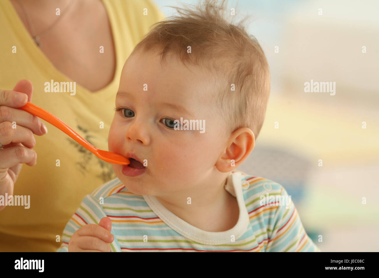 Dado, baby, 7 mesi, feed, abiti, mangiare, Indoor, boy, curiosità, cucchiaio, fame, Ritratto, Panorama, è sorpreso, persone, donna Foto Stock