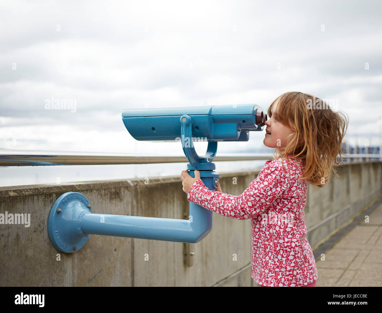 Bambino (6) utilizzando un binocolo pubblica sul lungomare di Wellington Foto Stock