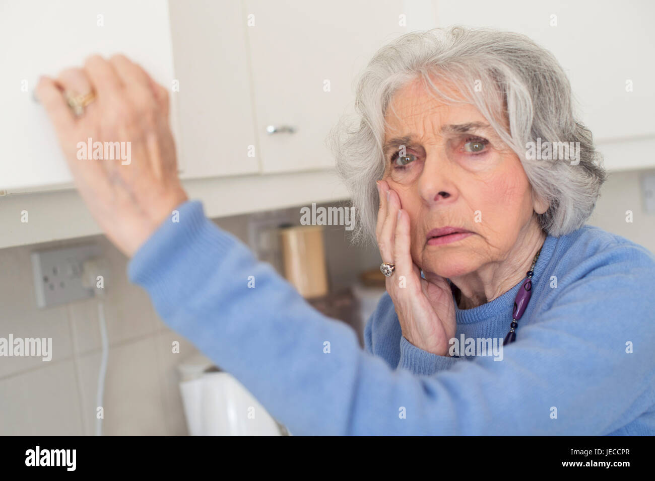 Dimentico Senior donna con demenza cercando in armadio Foto Stock