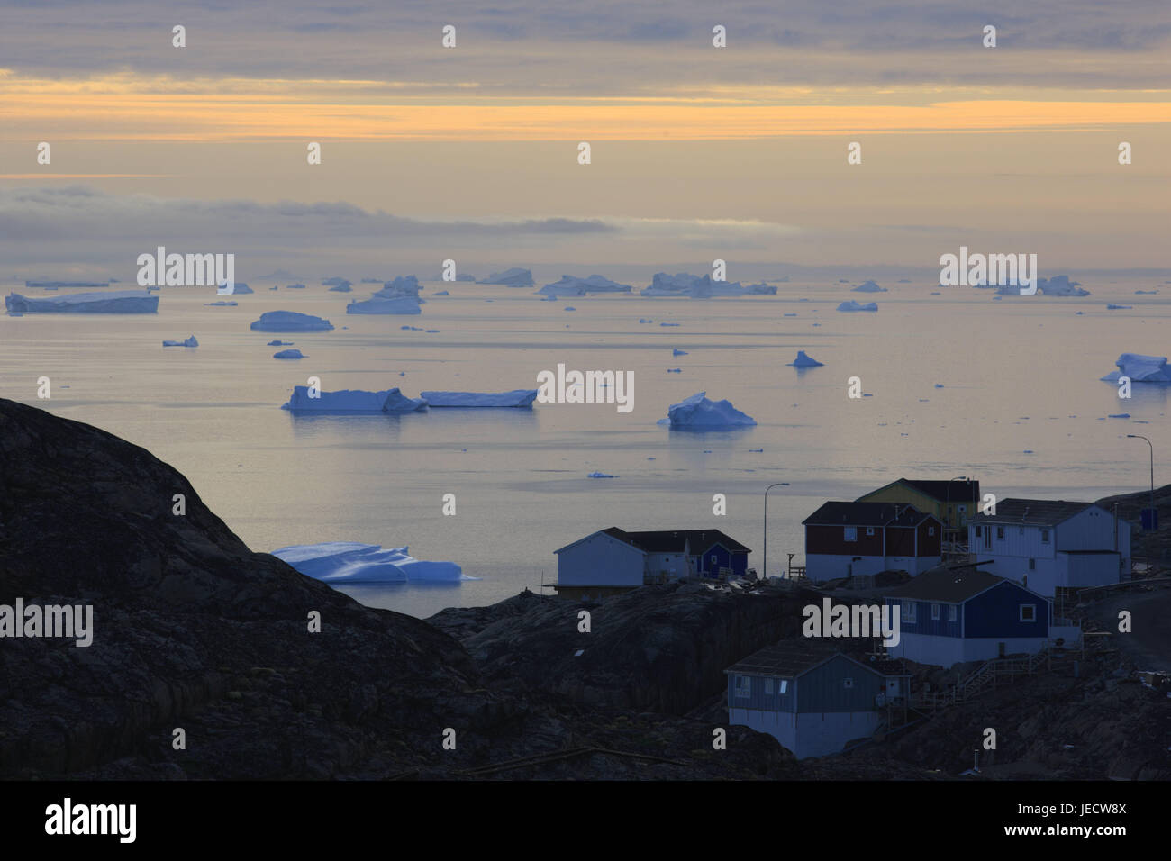 La Groenlandia, Uummannaq, case, costa, Fjord, iceberg, visualizzare, sera, nel nord della Groenlandia, destinazione, sul mare Artico, montagne, il ghiacciaio di gelati, fuori, e sharp, acqua, deserte, rocce, chiusura anomala, il ghiacciaio terminazione anomala, la deriva di ghiaccio freddo, riscaldamento climatico, case in legno, case residenziali, opaco, Foto Stock