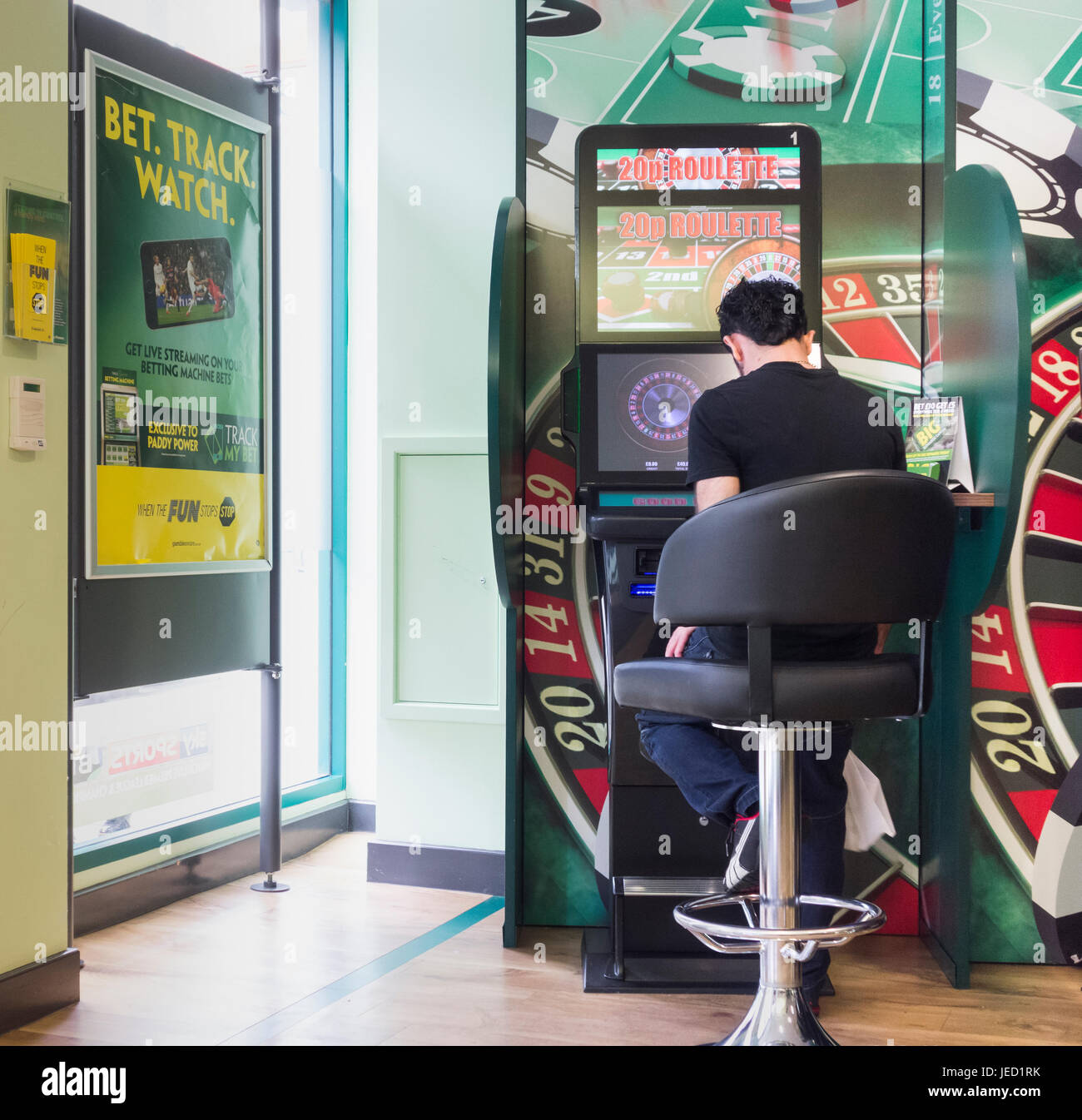 Uomo che utilizza il gioco di Roulette macchina (FOBT fixed odds betting terminale) in Bookmakers in Inghilterra, Regno Unito Foto Stock