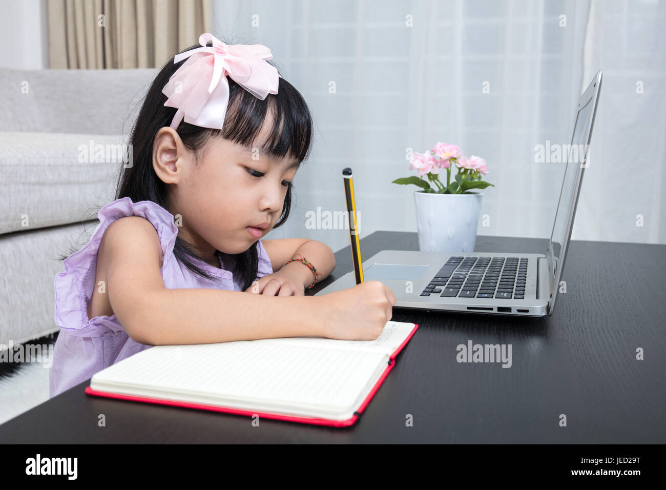 Cinese asiatici bambina facendo compiti a casa con il computer portatile  nel salotto di casa Foto stock - Alamy