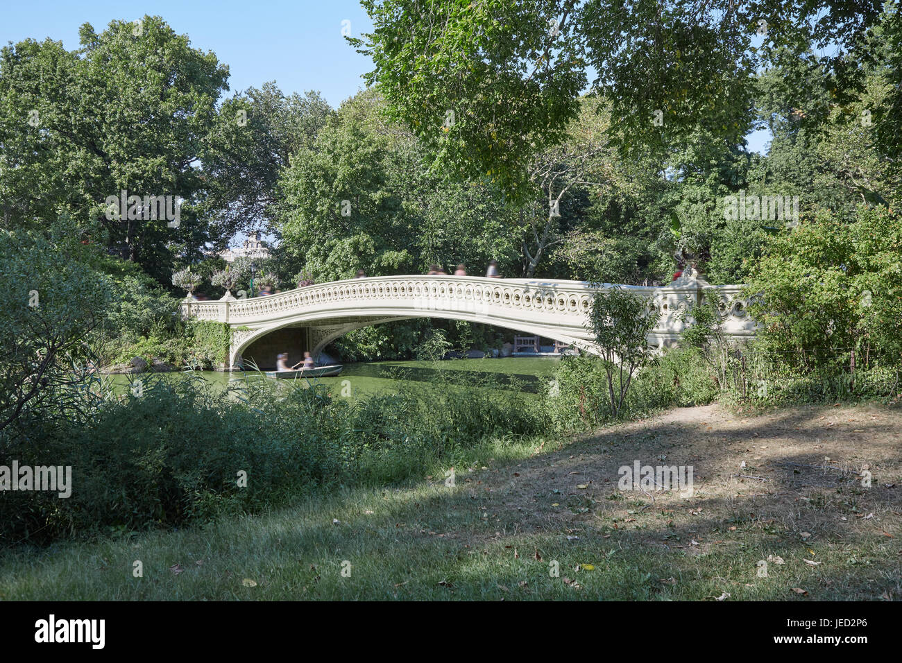 Central Park e bianco ponte di prua con persone di passaggio in una giornata di sole in New York Foto Stock