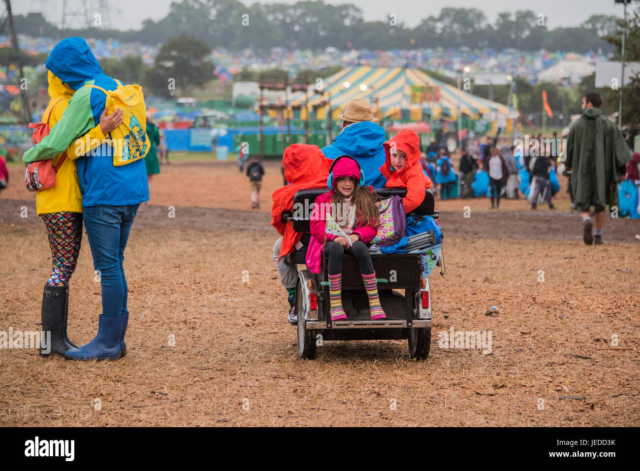 Glastonbury, Somerset, Regno Unito. Il 24 giugno 2017. Un paio di hu e i bambini godono la corsa sul loro papà della buggy. Un po' di pioggia leggera porta la impermeabilizza ma wellies sono una decisione split - Il 2017 Festival di Glastonbury, azienda agricola degna. Glastonbury, 23 giugno 2017 il credito: Guy Bell/Alamy Live News Foto Stock