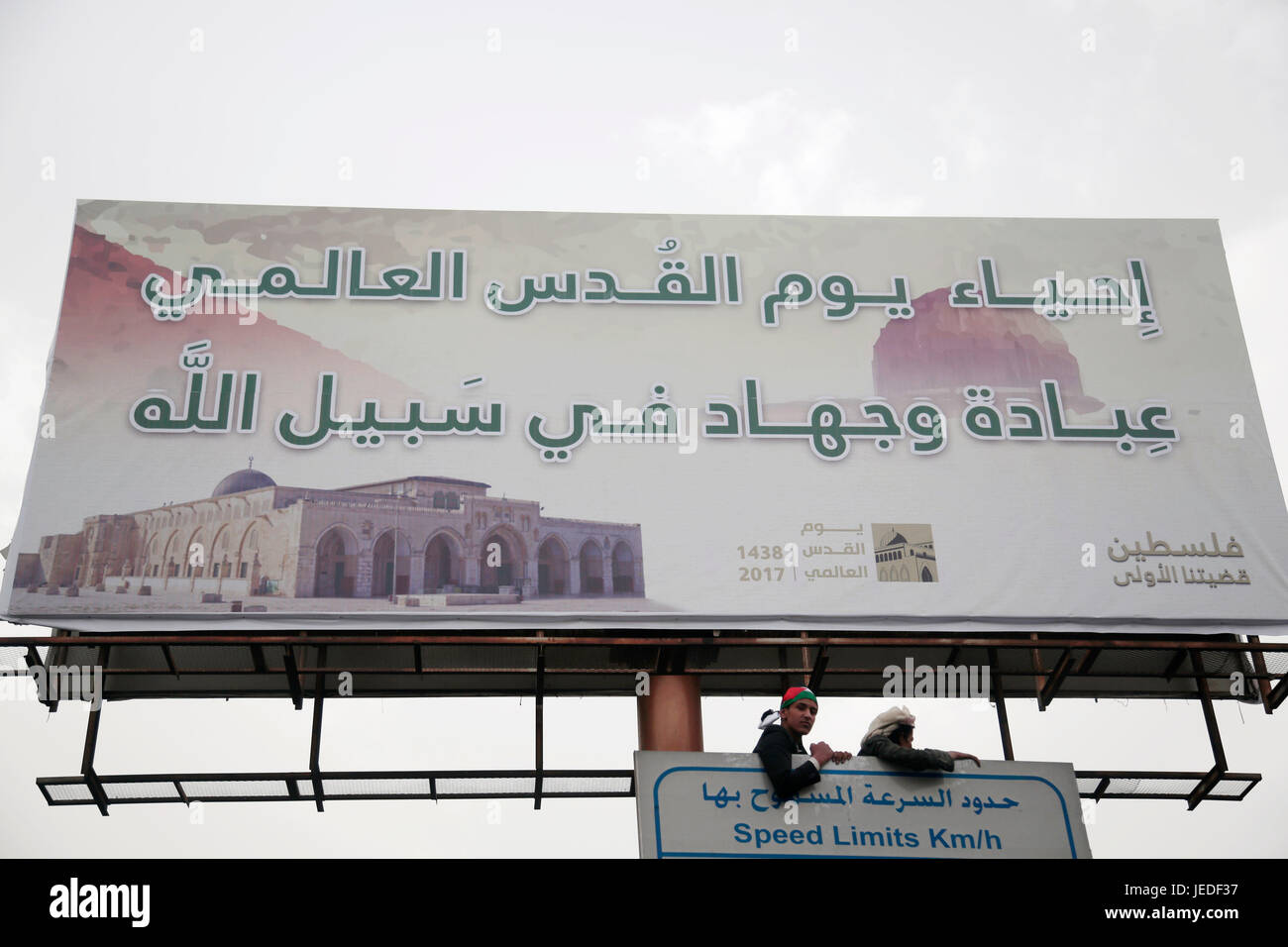 Due sostenitori dei ribelli Houthi sono visibili sotto un banner eretto con un messaggio a sollecitare popolo yemenita per prendere parte a una dimostrazione di marcatura giorno Quds (Gerusalemme giorno) a Sana'a, Yemen, 23 giugno 2017. Quds giorno viene mantenuto l'ultimo venerdì del musulmano il mese di digiuno del Ramadan. La manifestazione è stata avviata dall'Iran nel 1979 per esprimere il sostegno ai palestinesi. Foto: Hani Al-Ansi/dpa Foto Stock