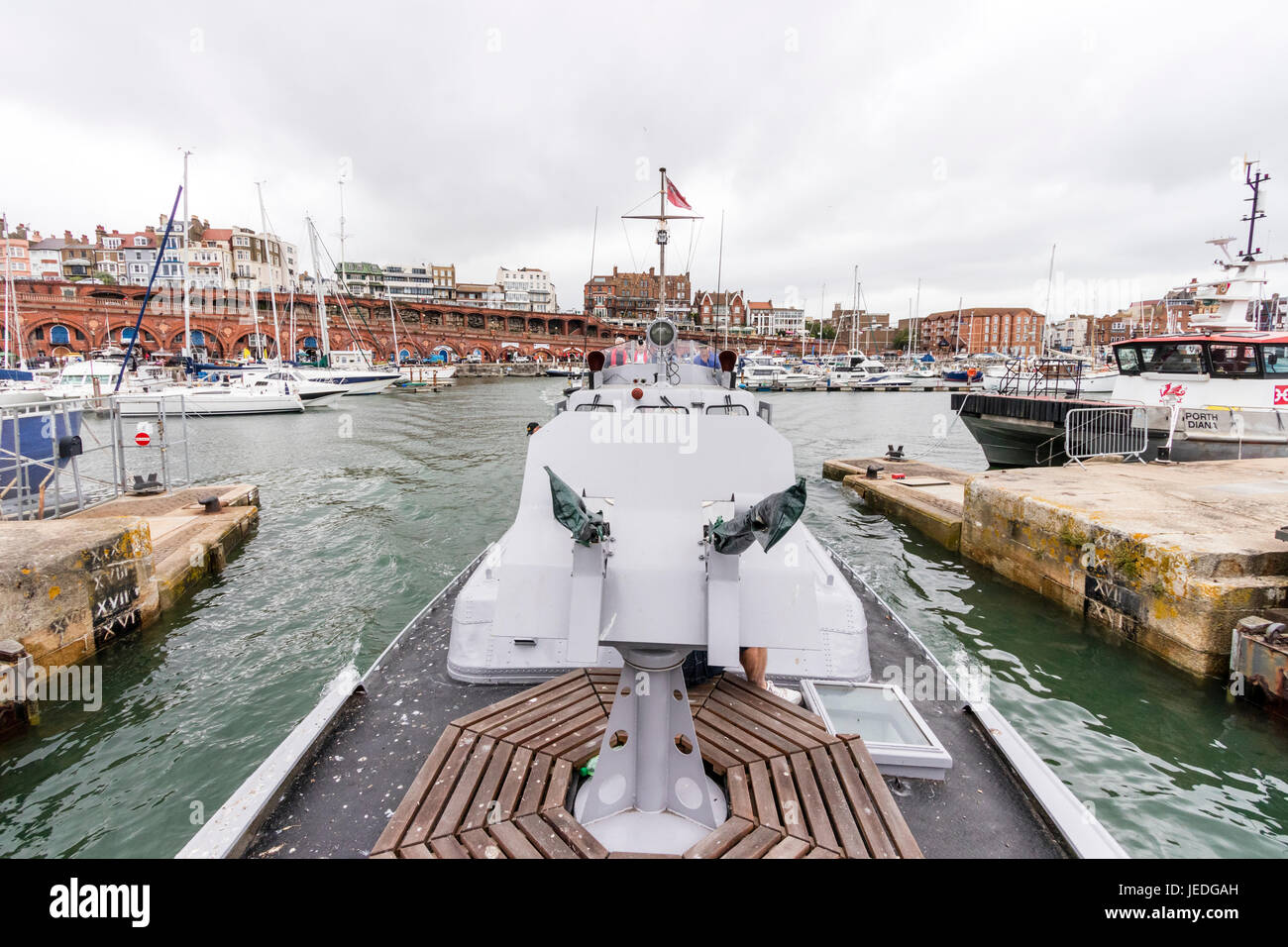 Bow veduta di mitragliatrice scudo e stazione, indietro lungo P22, restaurato fiume Reno imbarcazione di pattuglia, come lei passa attraverso la saracinesca del interna ed esterna al Porto di Ramsgate. Cielo nuvoloso, grigio cloud. Sfondo di Ramsgate porto e città. Foto Stock