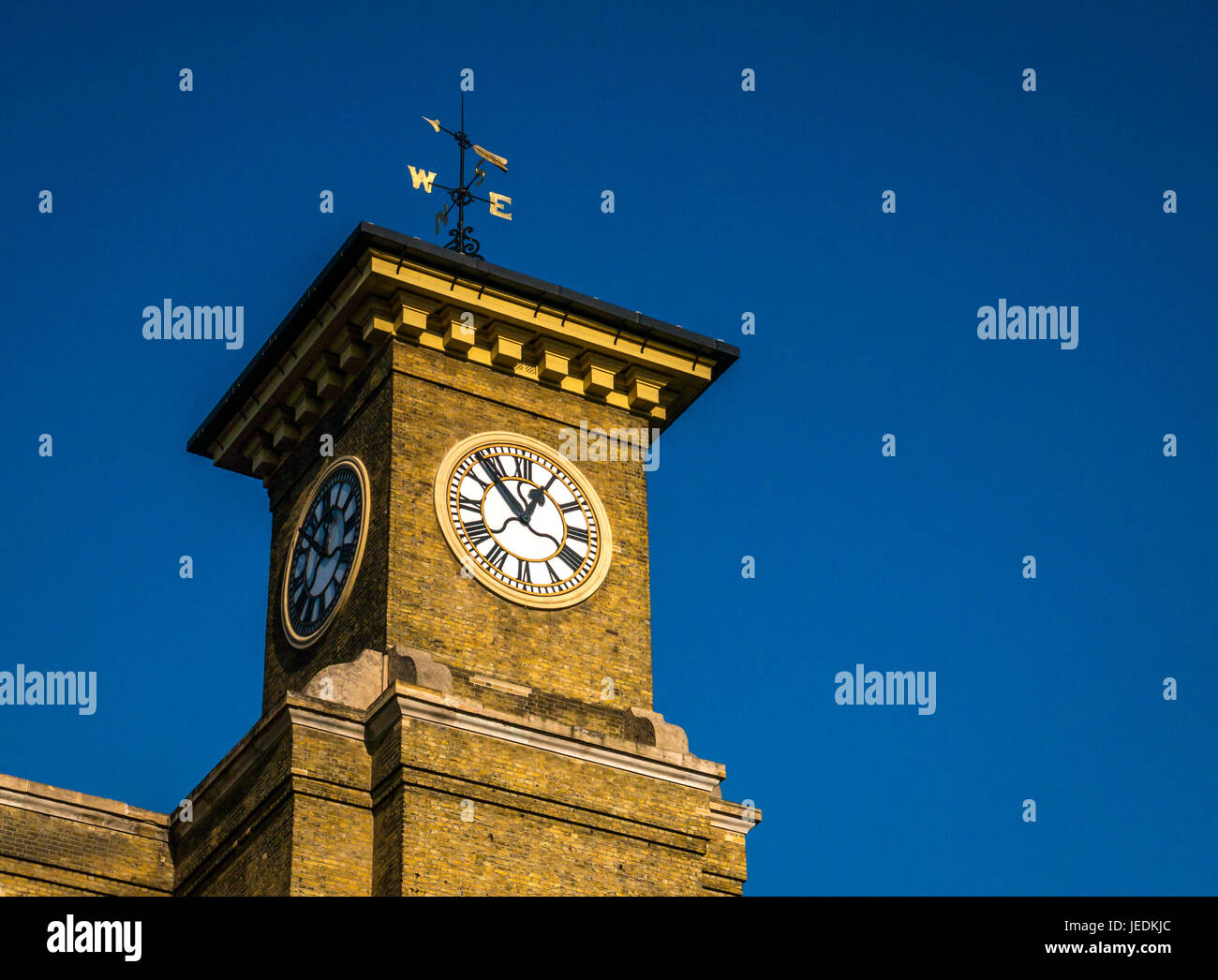 Vista ravvicinata del quadrante dell'orologio e del weathervane, torre vittoriana della stazione ferroviaria di King's Cross, Londra, Inghilterra, Regno Unito con cielo blu Foto Stock