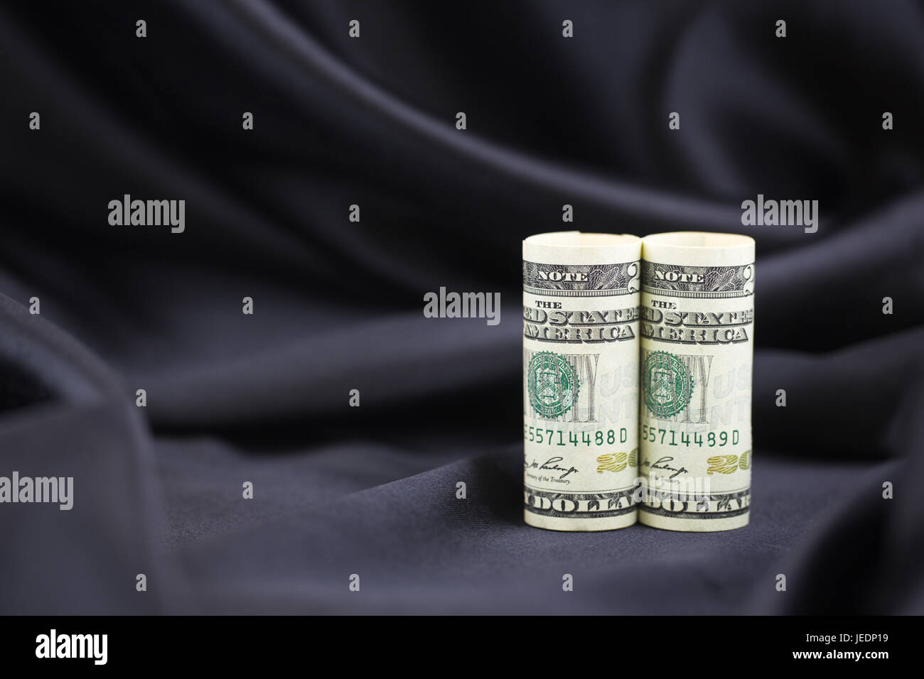 Coppia di dollari americani verticale contro elegante, semplice satin nero lo sfondo del potere riflettente e di successo. Foto Stock