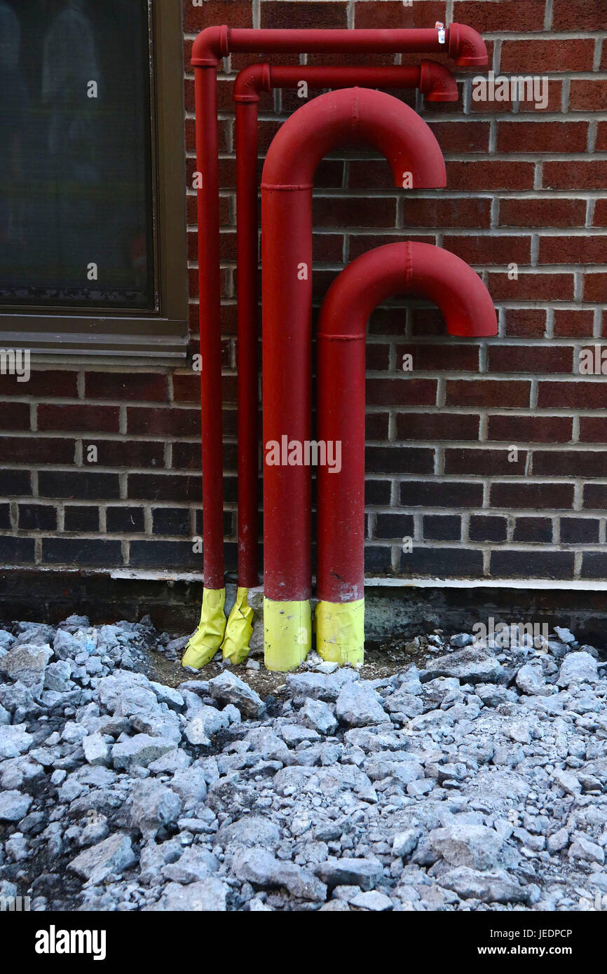 Candy Cane come tubazioni rosso contro un muro di mattoni con pietre Foto Stock
