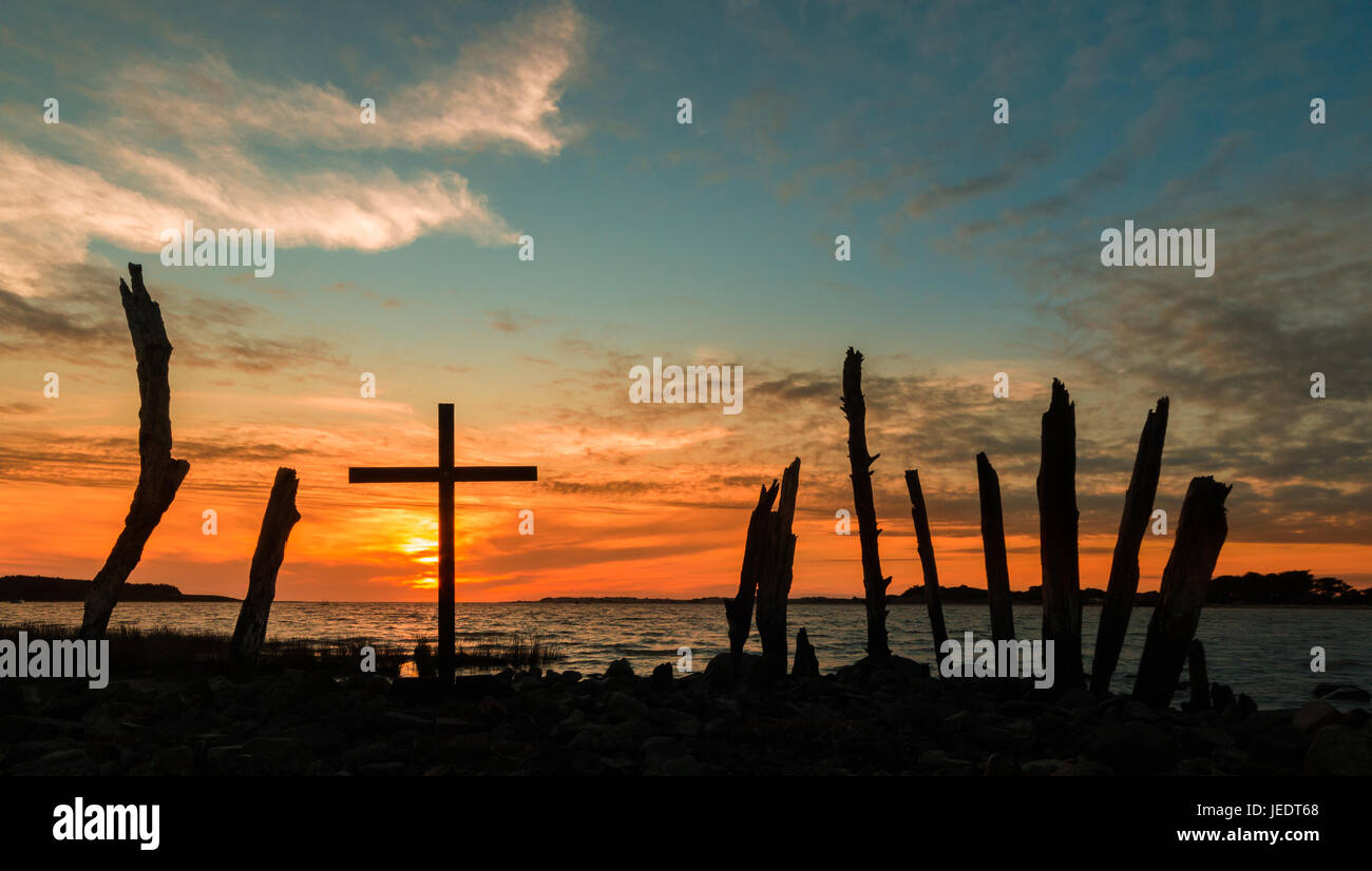 Croce nera con vecchi log intorno ad esso come va giù dietro di esso. Foto Stock