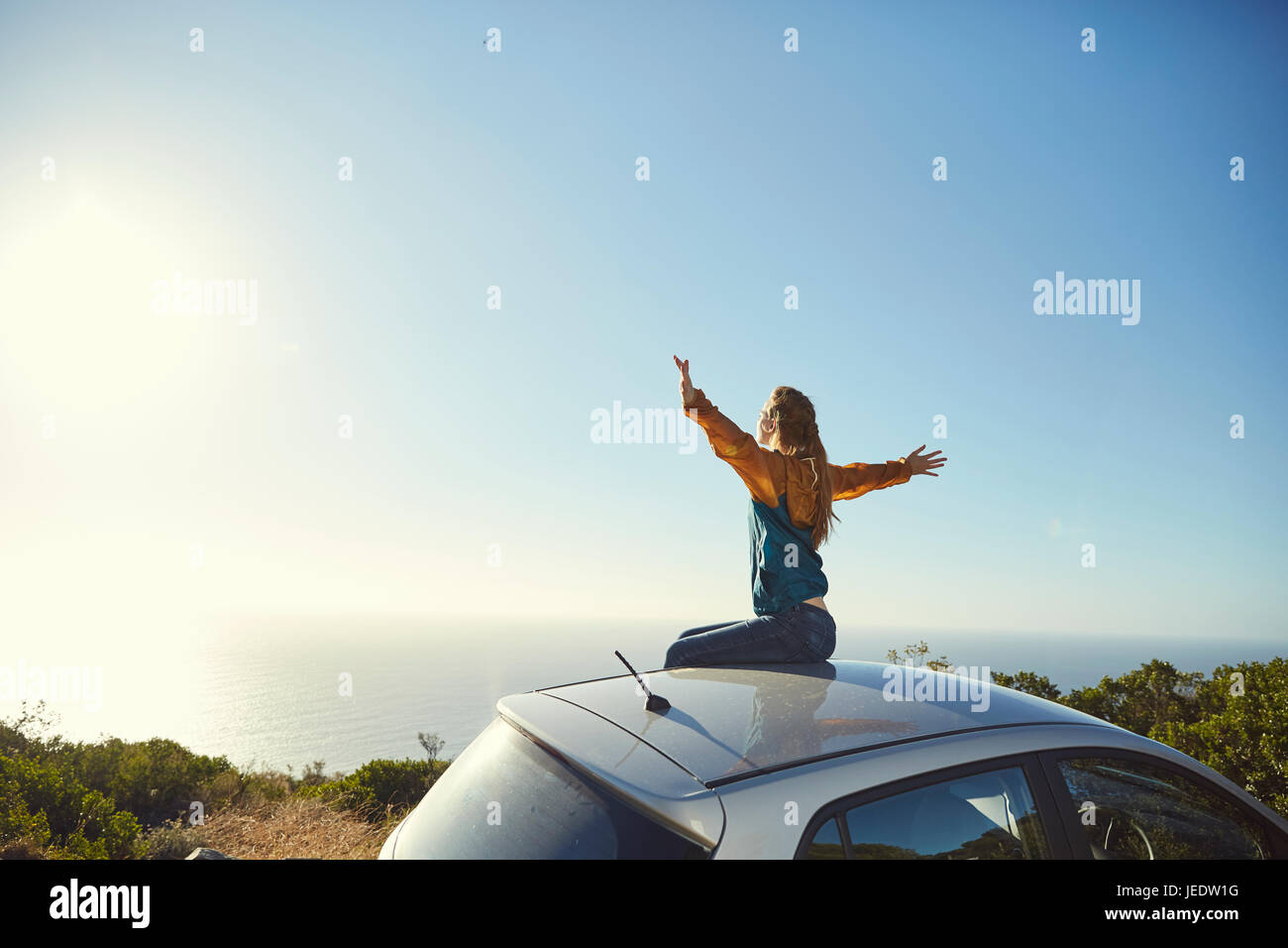 Sud Africa, Cape Town, Signal Hill, giovane donna seduta sulla parte superiore della vettura godendo della vista sul mare Foto Stock