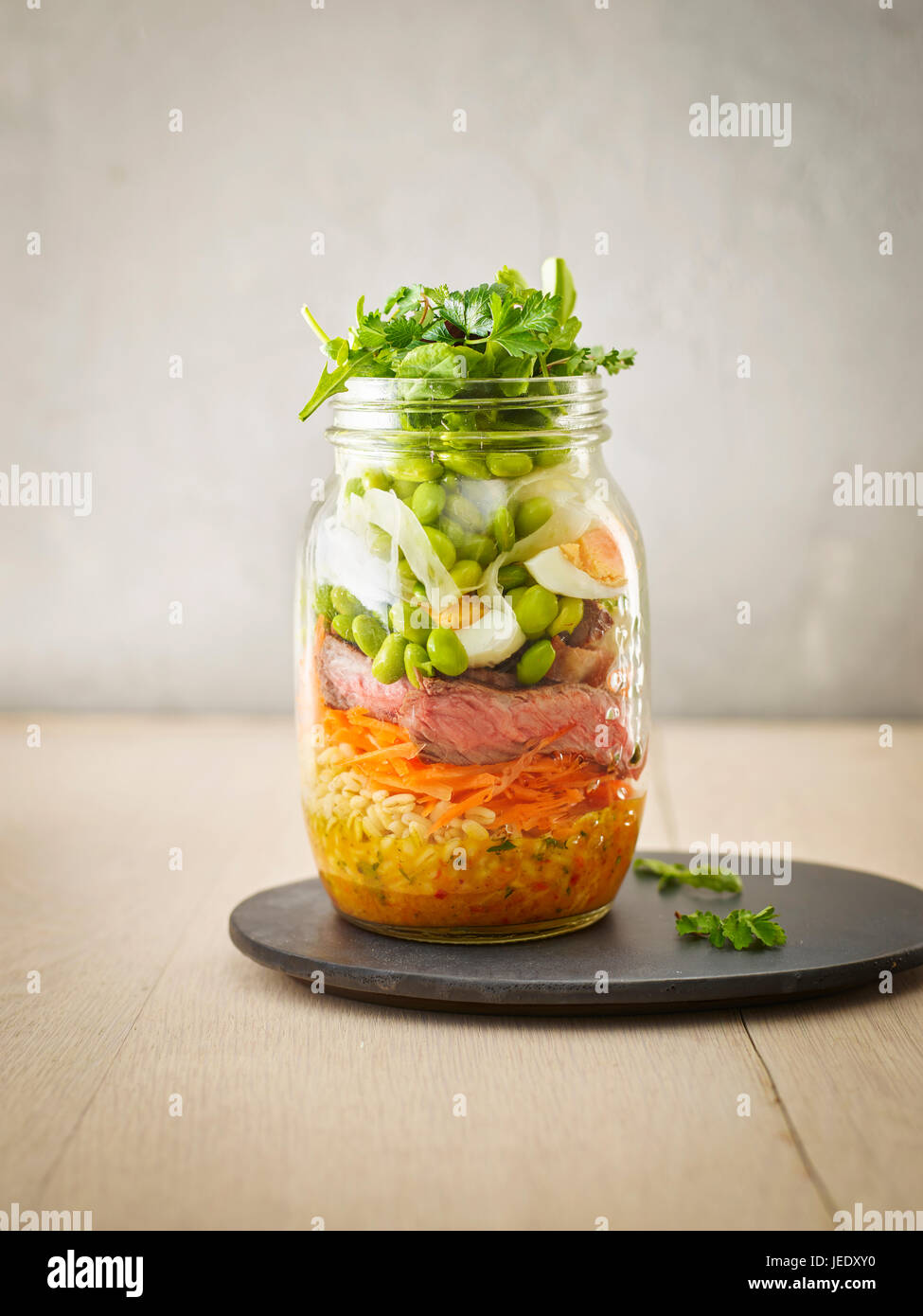 La conservazione di un vasetto di frumento con insalata di verdure, uova sode e fette di manzo Foto Stock