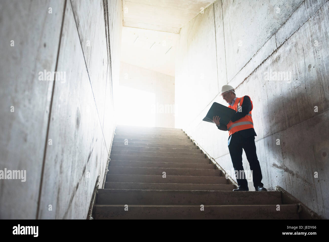 Uomo con documenti indossando giubbotto di sicurezza in edificio in costruzione Foto Stock
