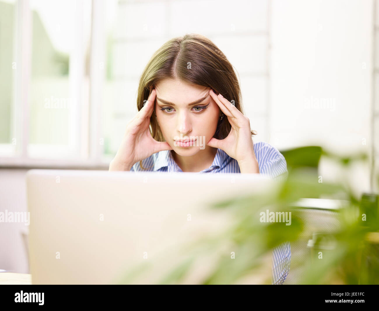 Giovane femmina caucasica business executive guardando laptop computer pensando hard in ufficio. Foto Stock