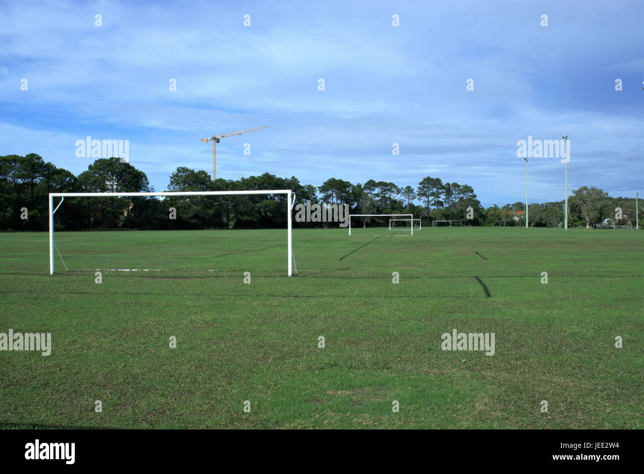 Parco giochi di calcio in Australia. Parco giochi di calcio con pali, proiettori, alberi e una gru in lontananza. Foto Stock