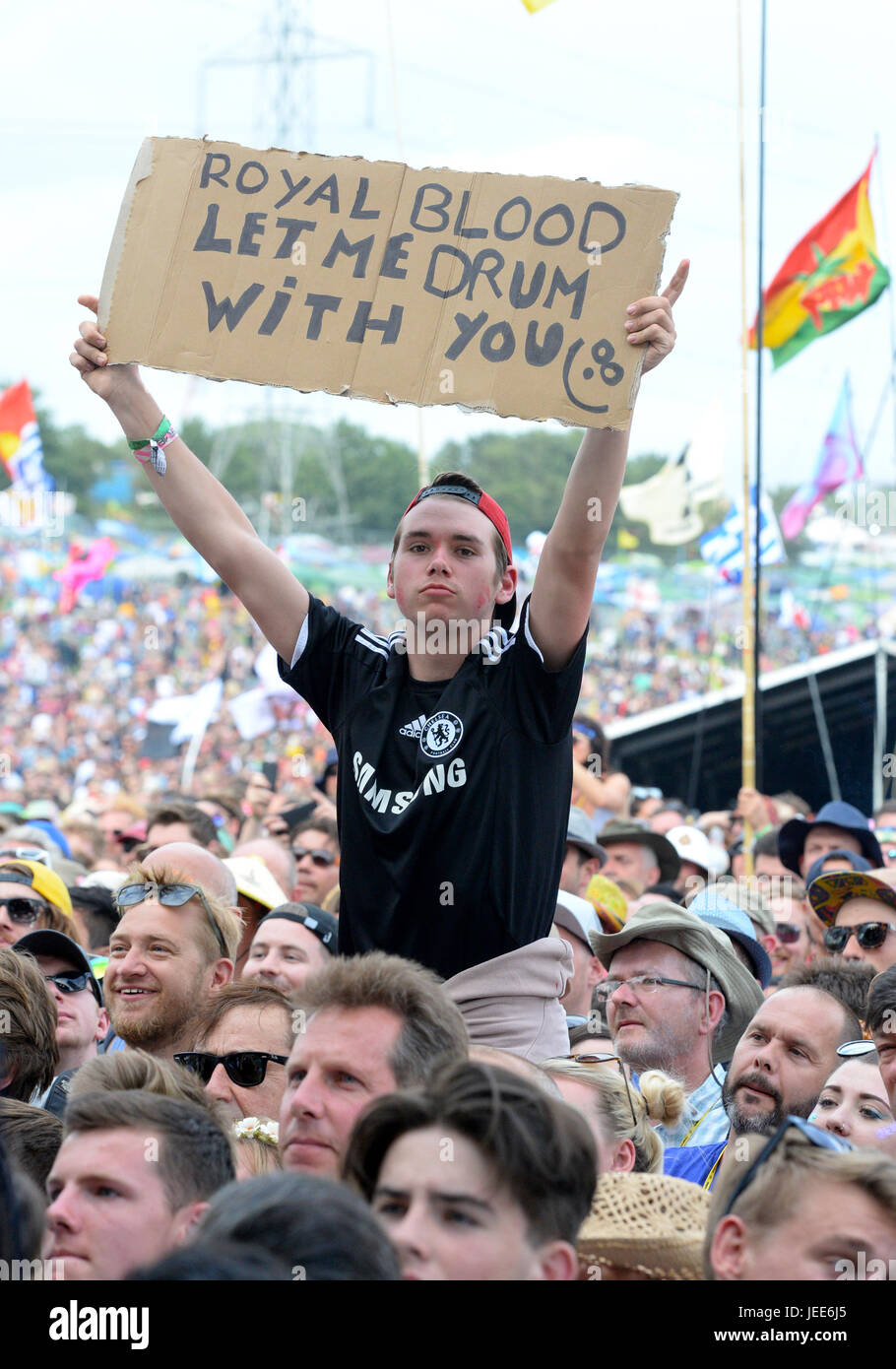 Un festivalgoer detiene un segno come egli orologi Royal sangue sulla fase della piramide presso il festival di Glastonbury, presso l'azienda agricola degna in Somerset. Foto Stock