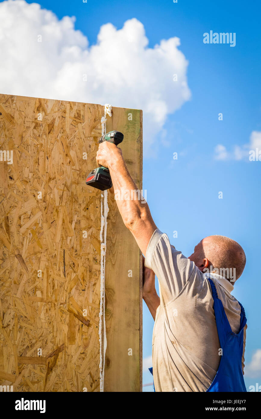 Il lavoratore si aggancia sorsi di legno pannello di una nuova casa Foto Stock