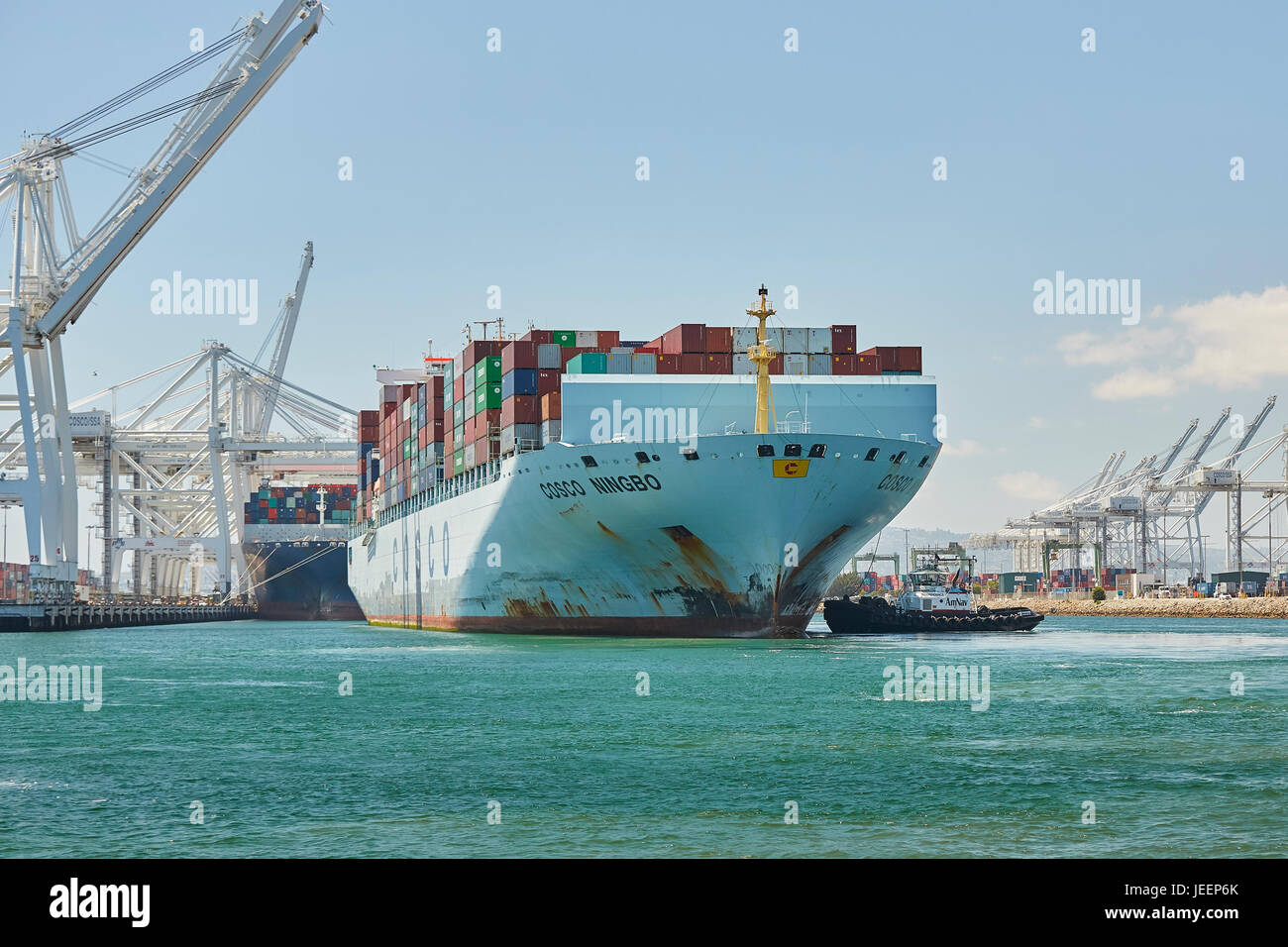 Il Gigante COSCO Container di Ningbo Nave è guidato in banchina J270 sul molo J dal AmNav Trattore rimorchiatore indipendenza alla lunga spiaggia terminale per container Foto Stock