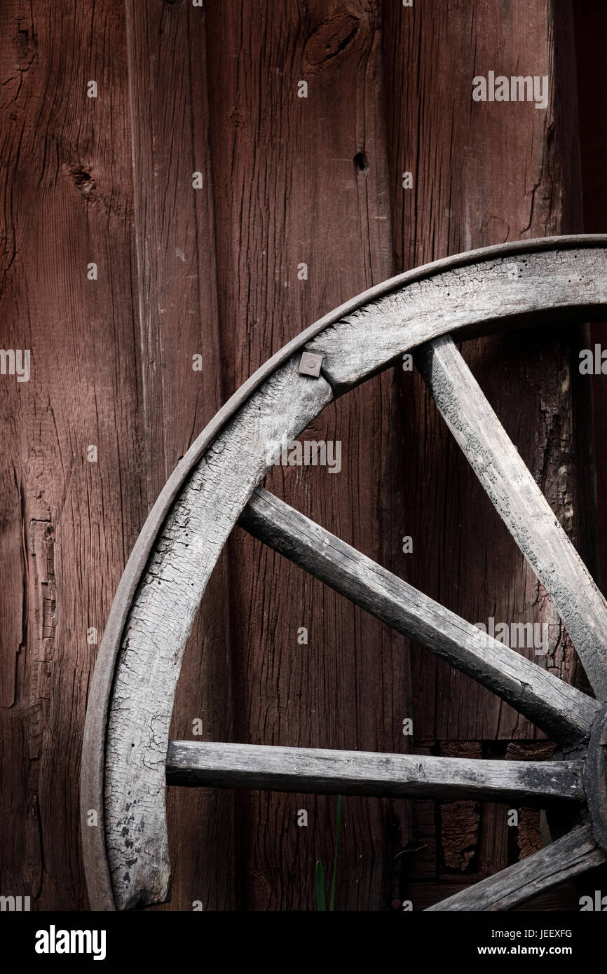 Vecchia ruota del carro al di fuori di edificio rurale parete. In legno rustico oggetto di nostalgia. Foto Stock