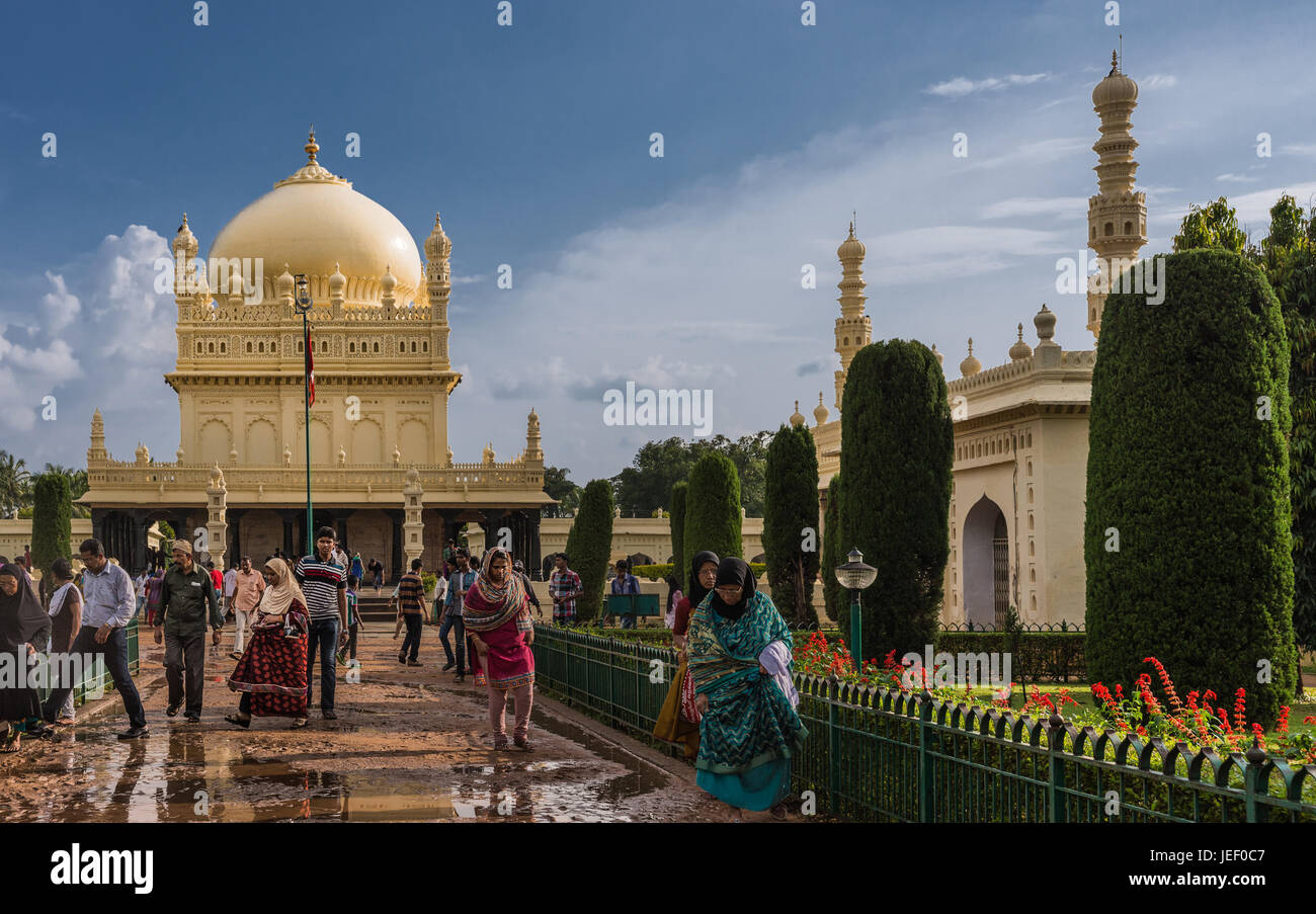 Mysore, India - 26 Ottobre 2013: crema gialla Sultano Tipu mausoleo con cupola e moschea sotto pesante cloudscape. La gente a piedi e da costruire Foto Stock