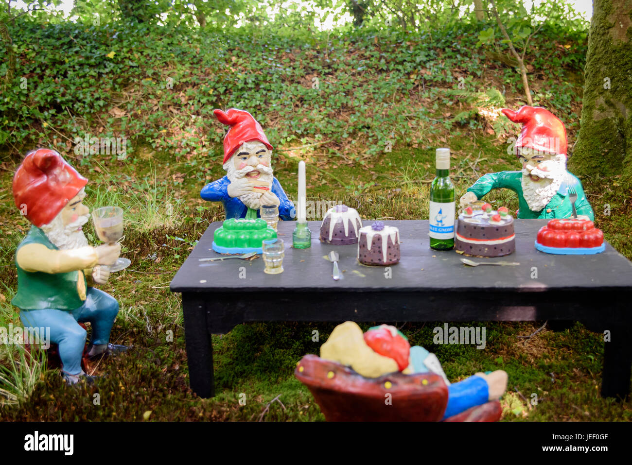 Gli gnomi seduti intorno ad un tavolo per mangiare la torta e bere Foto Stock